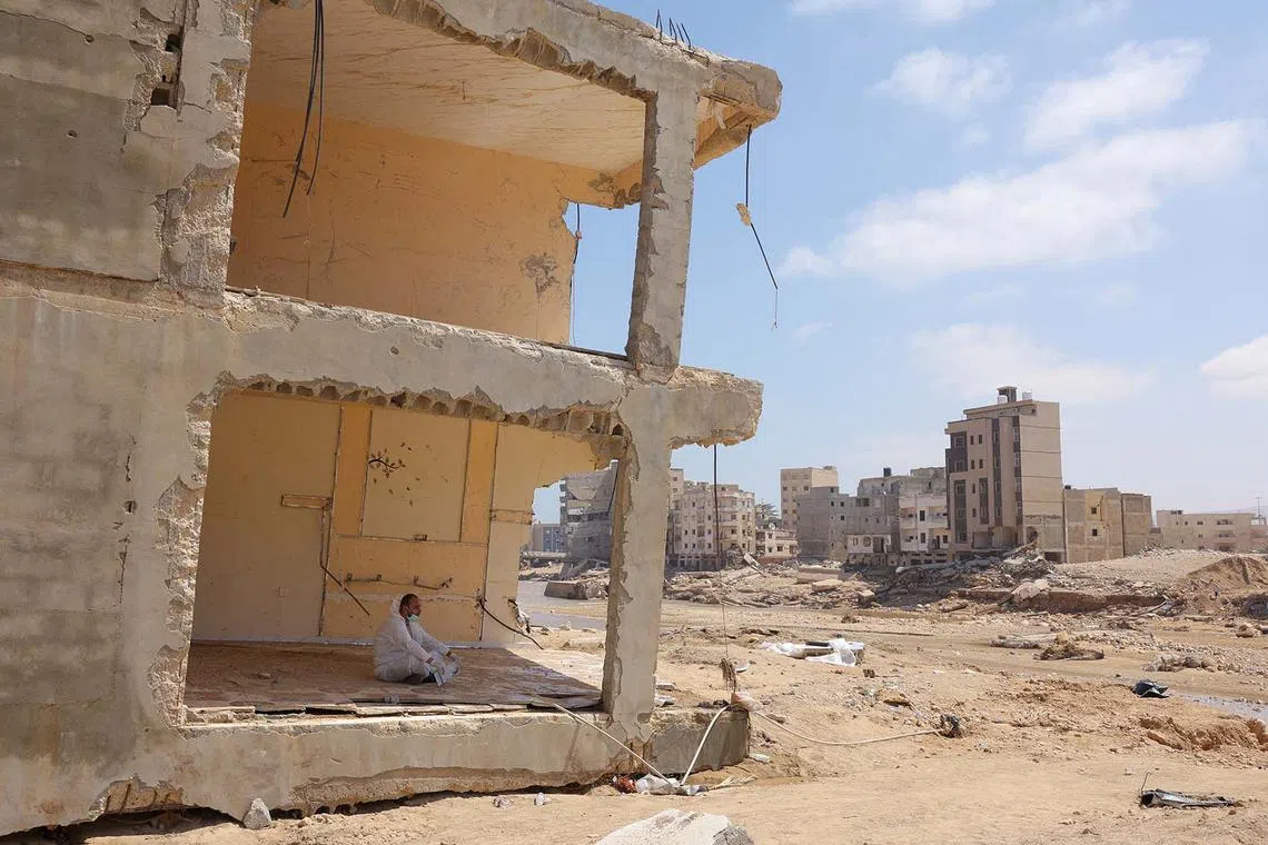 A volunteer rests inside a destroyed home following fatal floods in Derna, Libya, Sept 16.
