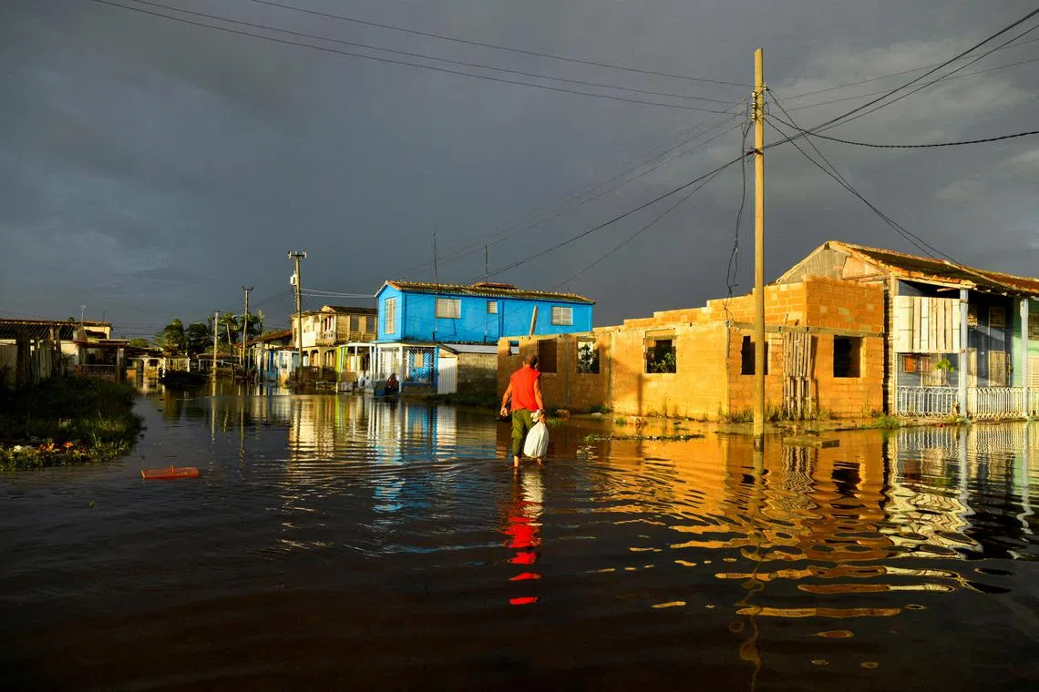 FILE PHOTO: A man walks in a flooded street a day after Hurricane Rafael made landfall in Batabano, Cuba, November 7, 2024. REUTERS/Norlys Perez/File Photo