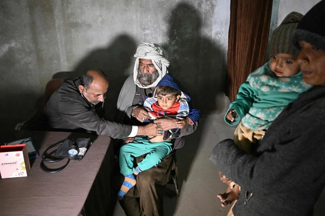 Mr Abdul Waheed (left) trying to diagnose a minor in his unlicensed clinic on the outskirts of Hyderabad city in Sindh province on Jan 8. Clinics like his are often the first point of care for poor communities.