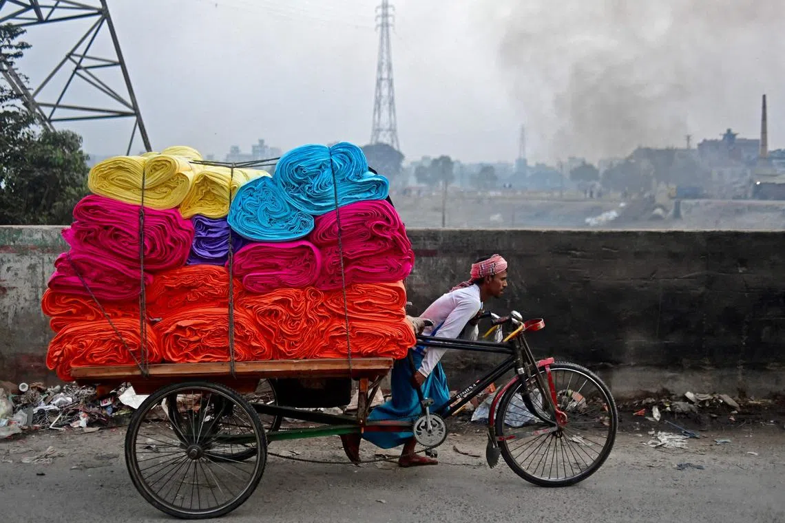 A worker pulls his rickshaw loaded with bundles of cloth in Dhaka on Jan 9, 2023.