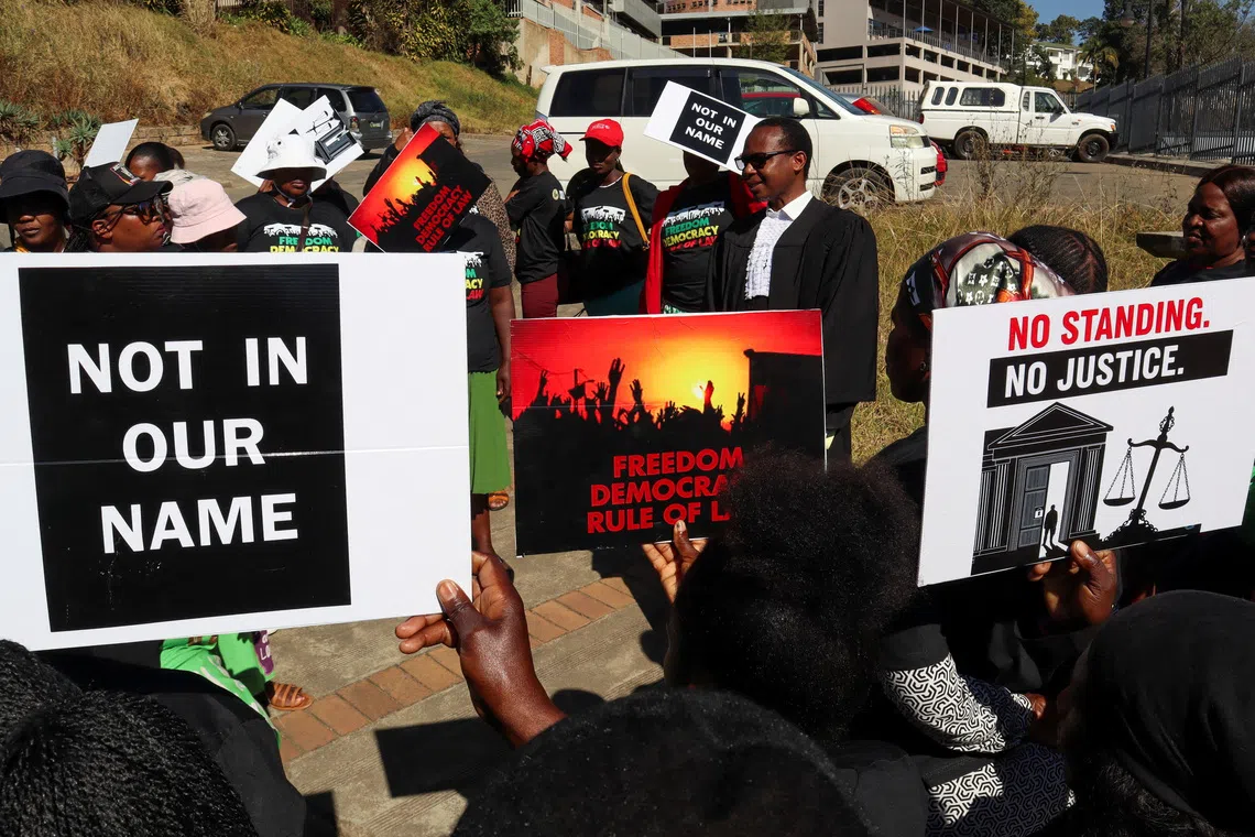 Protesters hold placards as lead applicant and lawyer Mzwandile Masuku addresses them outside the court in Mbabane, Eswatini, August 22, 2025. Activists are challenging a secretive agreement with former U.S. President Donald Trump's administration to accept third-country deportees, which they argue is unconstitutional. REUTERS/Zakhele Mabuza