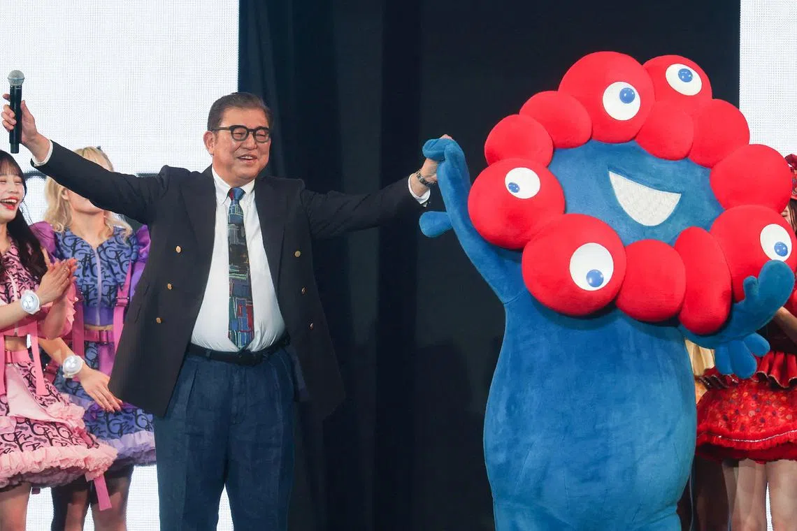 Mr Ishiba (left) stands with Myaku-Myaku, the mascot for the 2025 Osaka World Expo, as he models an outfit during a visit to the Tokyo Girls Collection fashion event.