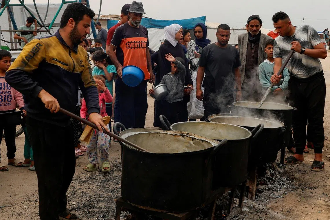FILE PHOTO: Palestinians gather to receive food cooked by a charity kitchen, in Khan Younis, southern Gaza Strip, April 8, 2025. REUTERS/Hatem Khaled/File Photo