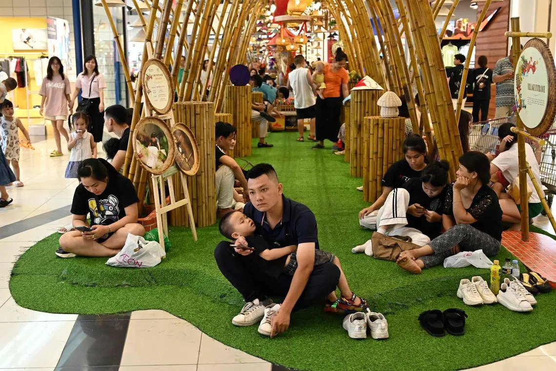 People resting inside a shopping mall to escape high temperatures in Hanoi on June 3.