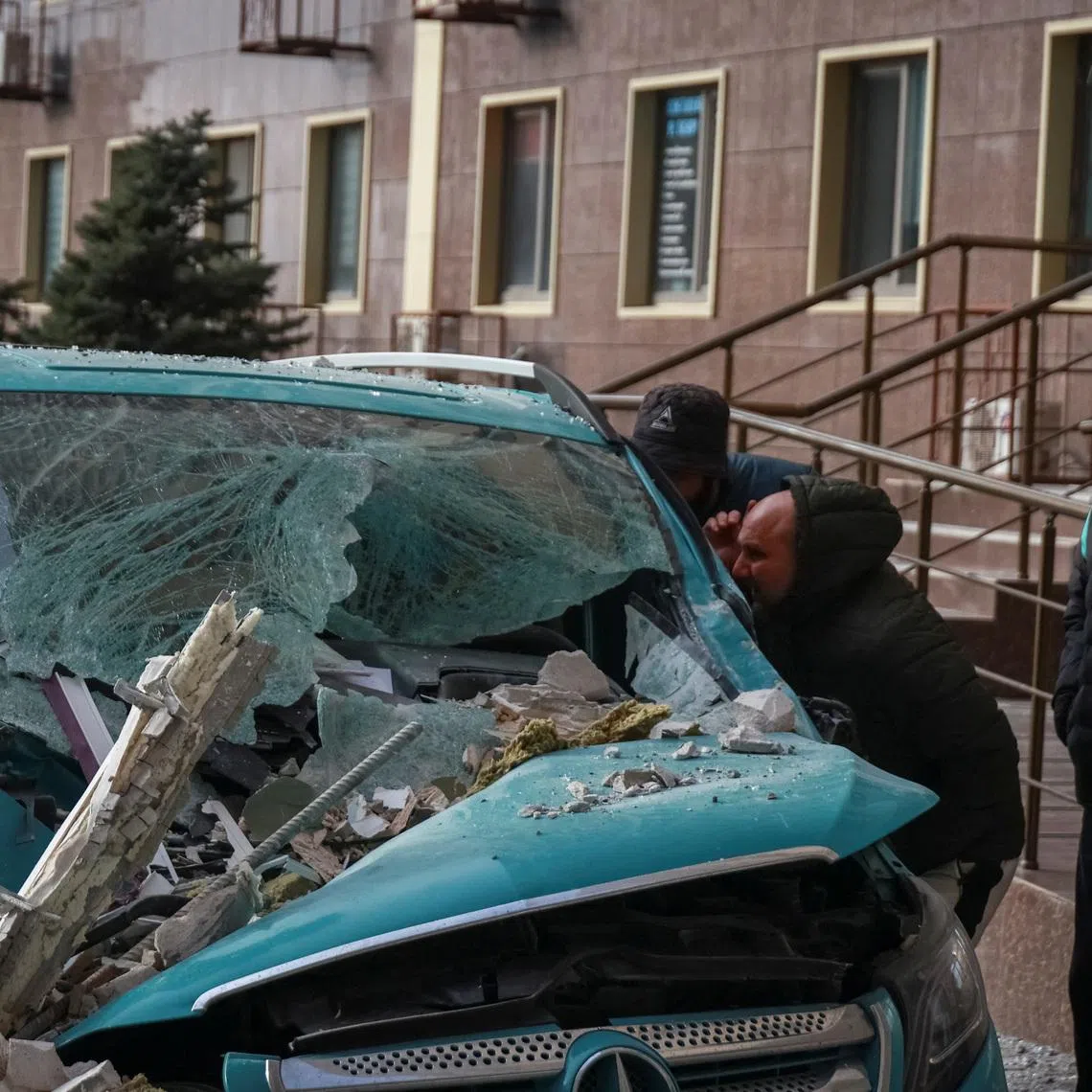 Residents observe a damaged car at the site of the Russian drone strike, amid Russia's attack on Ukraine, in Odesa, Ukraine January 19, 2026. REUTERS/Nina Liashonok