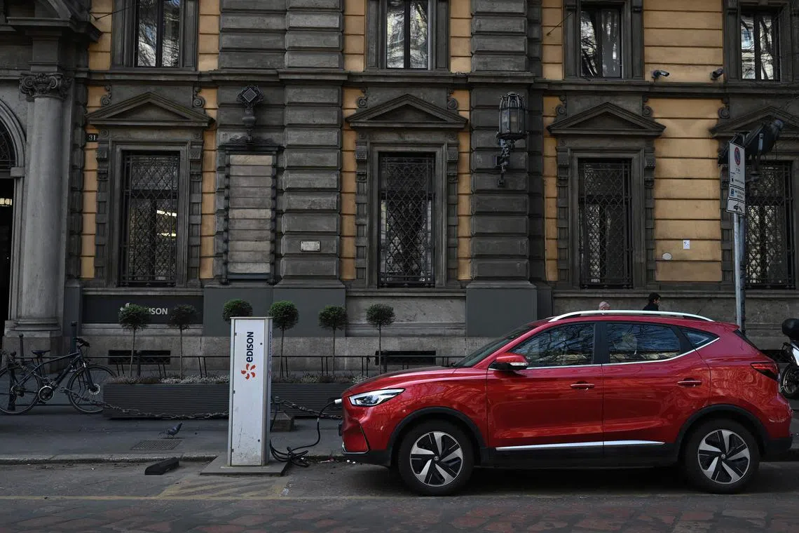 (FILES) In this file photo taken on March 23, 2023, an MG electric SUV charges at a hub in downtown Milan. - The 27 EU member states approved Monday a deal between Brussels and Germany that lifted Berlin's block on a planned phaseout of new sales of fossil fuel cars by 2035. (Photo by GABRIEL BOUYS / AFP)