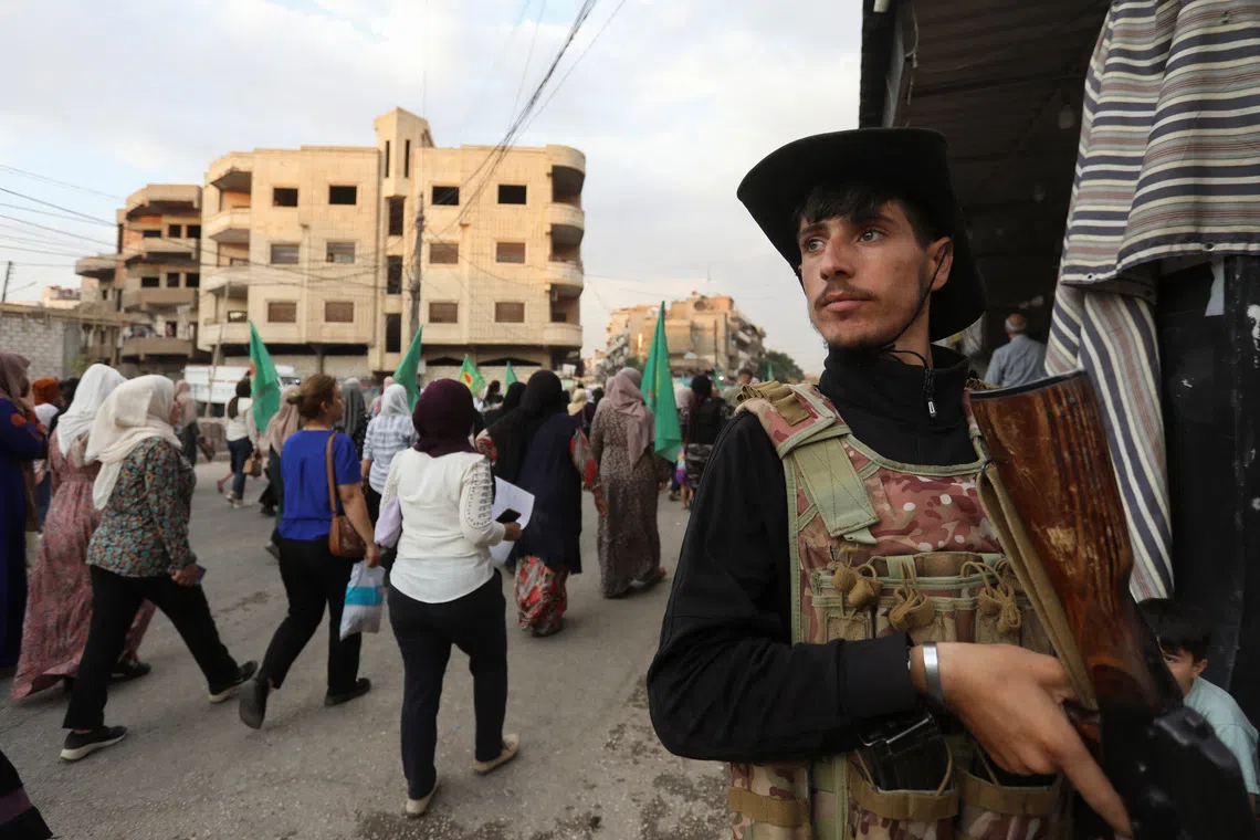 FILE PHOTO: A member of the Kurdish-led Syrian Democratic Forces (SDF) stands guard as Syrian Kurds attend a protest in solidarity with people in Sweida, after scores of people have been killed this week in violence in and around the predominantly Druze city of Sweida, pitting fighters from the Druze minority against government security forces and members of Bedouin tribes, in Qamishli, Syria July 17, 2025. REUTERS/Orhan Qereman/File Photo