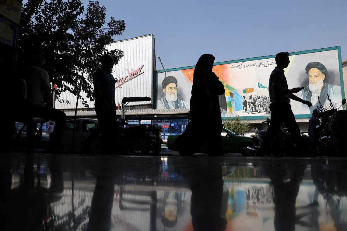 FILE PHOTO: People walk past a mural depicting the late leader of the Islamic Revolution Ayatollah Ruhollah Khomeini and Iran's Supreme Leader Ayatollah Ali Khamenei on a building in a street in Tehran, Iran, October 7, 2024. Majid Asgaripour/WANA (West Asia News Agency) via REUTERS/File Photo