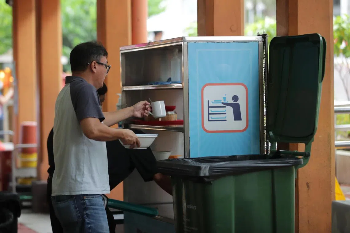 A diner returning used trays and crockery during lunch time at Maxwell Food Centre on June 1, 2023.