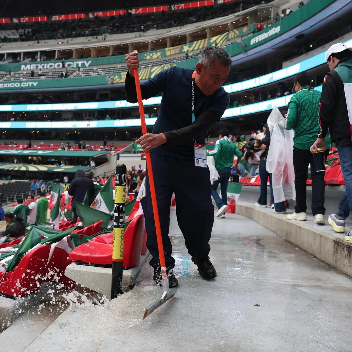 Staff at the Azteca Stadium sweeping rain water inside the stadium before the Mexico v England match on July 5.