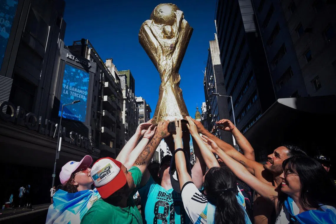 Argentina fans at the Obelisco holding a World Cup trophy replica after the victory parade was cancelled because of the. large crowd.