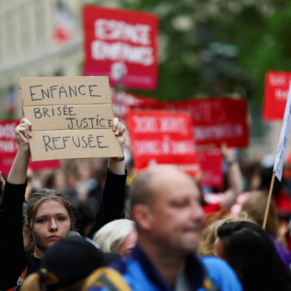 People attend a demonstration, amid nationwide calls to protest the handling by the criminal justice system of previous complaints involving child victims against the main suspect in the killing of 11-year-old Lyhanna, whose body was discovered near Fleurance after a days-long search, near the  Paris courthouse, France, June 8, 2026, in a protest supported by the #NousToutes movement. The sign reads: \"Broken childhood, justice denied\". REUTERS/Gonzalo Fuentes