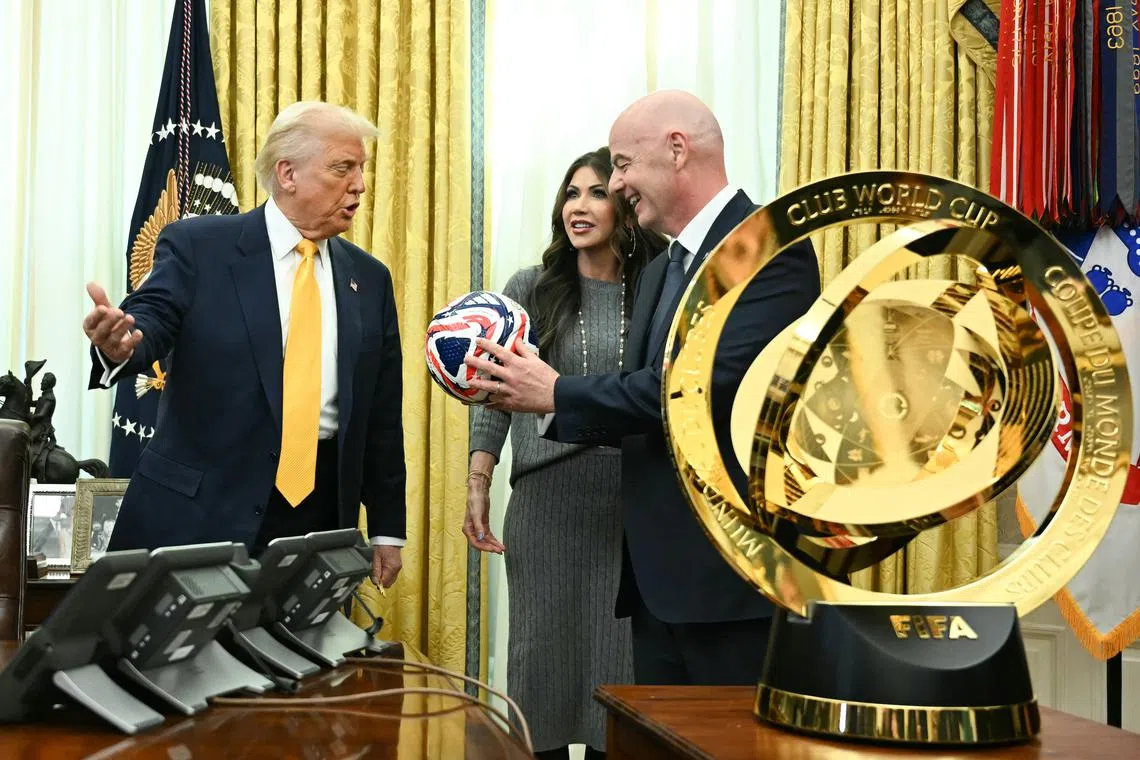 US President Donald Trump being shown the new Fifa Club World Cup trophy and official ball on March 7 by Fifa president Gianni Infantino, with US Secretary of Homeland Security Kristi Noem looking on.