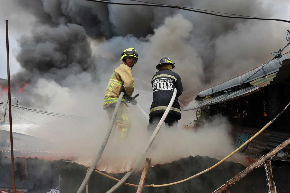 Firefighters hose burning shanties as a fire engulfs a slum area in Paranaque city in Metro Manila, the Philippines, on May 18. The authorities reported that scores of firefighters were injured when a fire truck overturned while responding to the fire, and dozens of families were rendered homeless. 