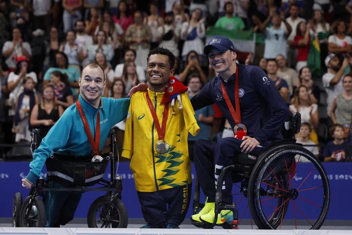 Gold medallist Gabriel Geraldo dos Santos Araujo of Brazil celebrates on the podium with silver medallist Vladimir Danilenko of Neutral Paralympic Athletes
and bronze medallist Alberto Caroly Abarza Diaz of Chile.
