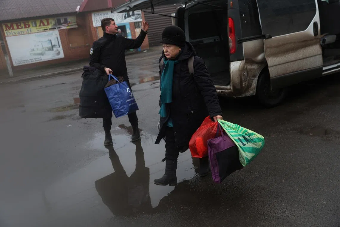 Valentyna, 70, walks with Leonid, a member of the volunteer organisation Chaplain Patrol, as she arrives at the Pokrovsk train station after being evacuated from Bakhmut, en route to meet her son in Kyiv, Ukraine.