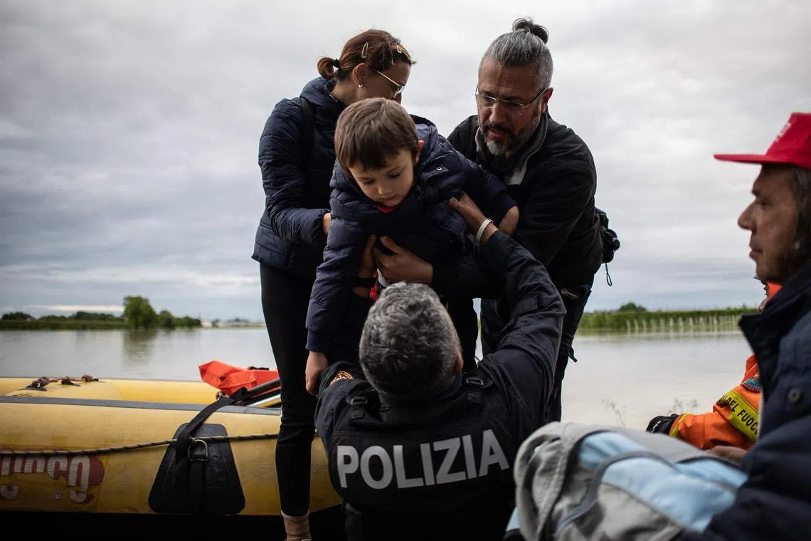 A policeman holds a boy during rescuing operations on May 17, 2023 in Massa Lombarda, Italy. 