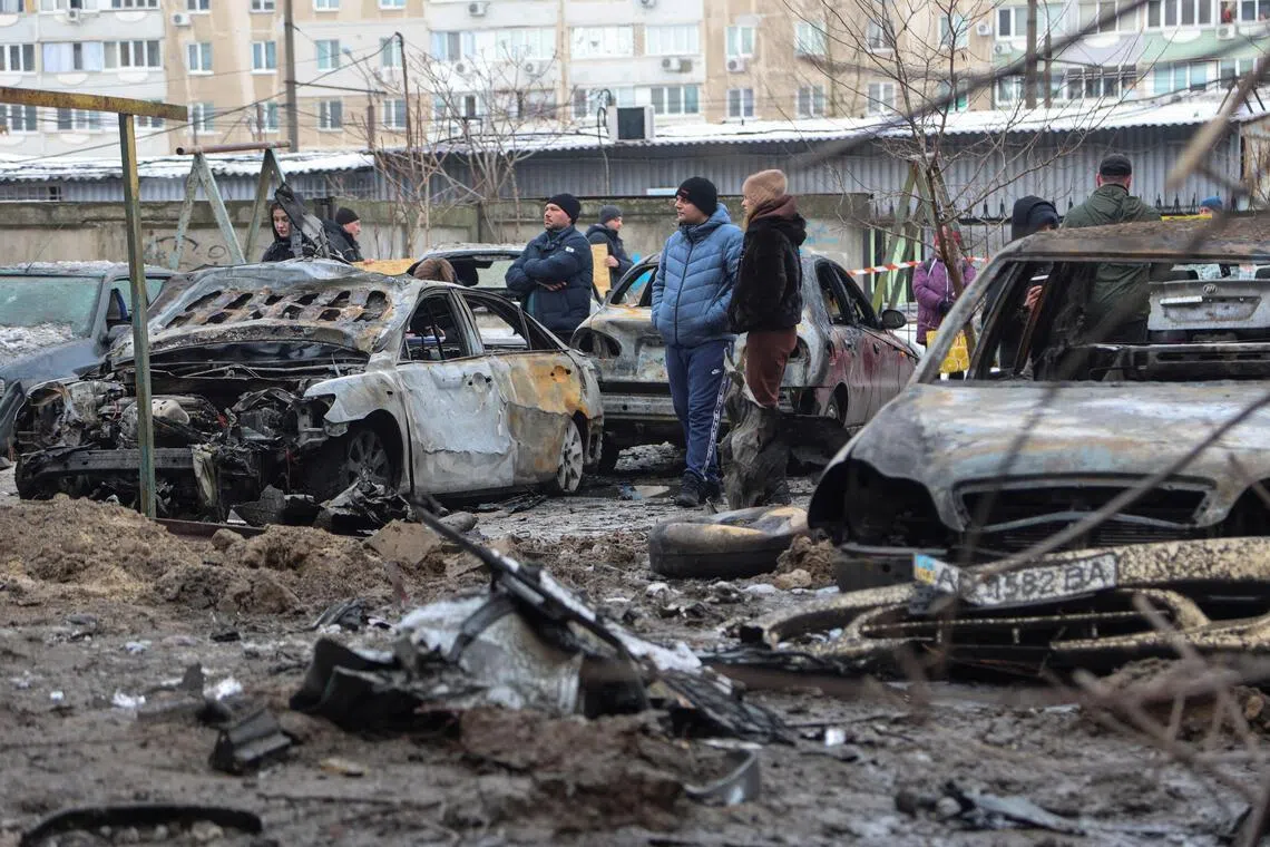 Residents standing at the site of an overnight attack by Russian drones and missiles in the Ukrainian city of Zaporizhzhia, on Jan 28.