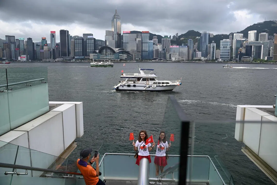 A pro-Beijing supporter waves a China and Hong Kong flag on the edge of Hong Kong’s Victoria Harbour as the city marks the 27th anniversary of the Handover of Hong Kong from Britain to China on July 1, 2024. (Photo by Peter PARKS / AFP)