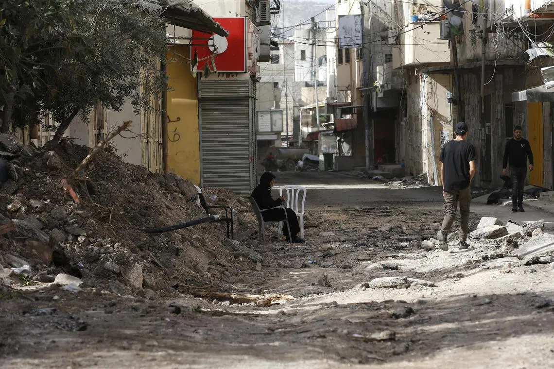 People walk amid the rubble in a street after an Israeli raid on the Jenin refugee camp in West Bank on Nov 26. 