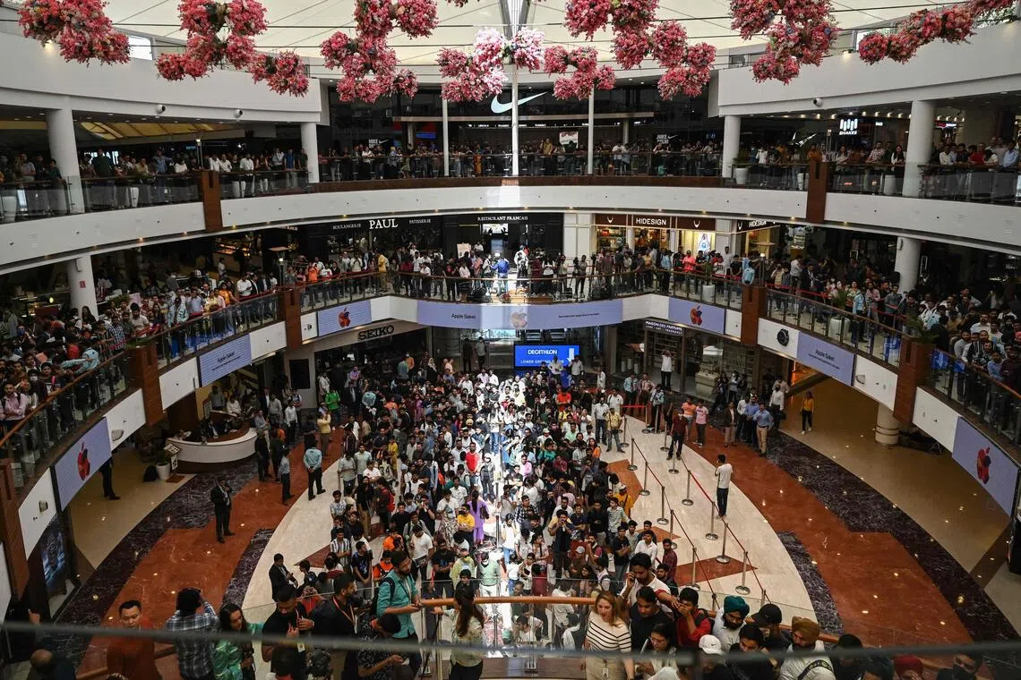 People wait at a mall before the opening of New Delhi's first Apple retail store at a mall in New Delhi on April 20.