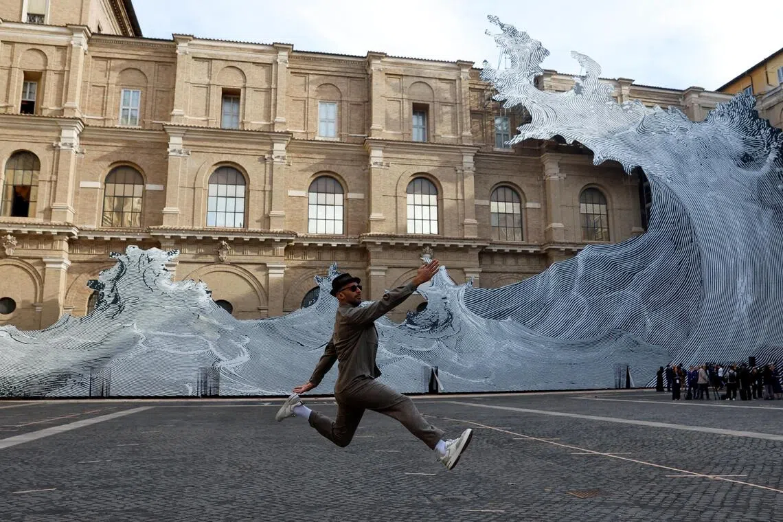 French artist JR performs one of his characteristic jumps as he poses in front of his installation "DILUVIUM" ahead of a visit by Pope Leo to inaugurate the exhibition "AQVA - Catastrophe and Wonder" at the Vatican Apostolic Library, at the Vatican, September 14, 2026. REUTERS/Vincenzo Livieri     TPX IMAGES OF THE DAY     