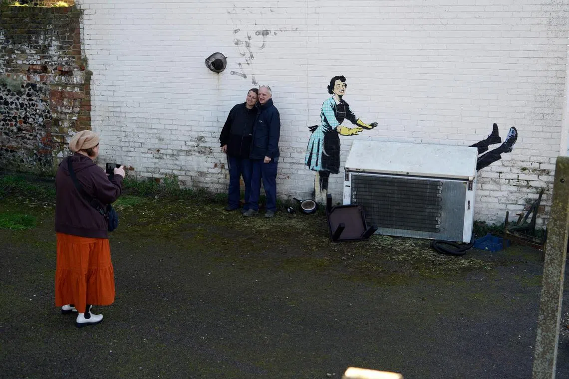 Members of the public look and take pictures of an artwork, on the side of a house in Margate, south- east England.