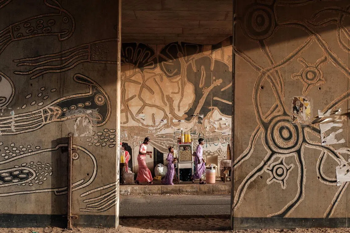 People in traditional clothes walking under a bridge near the Monument de la Renaissance as Muslims celebrate Eid al-Fitr marking the end of the holy fasting month of Ramadan, in Dakar, on April 10, 2024. 
