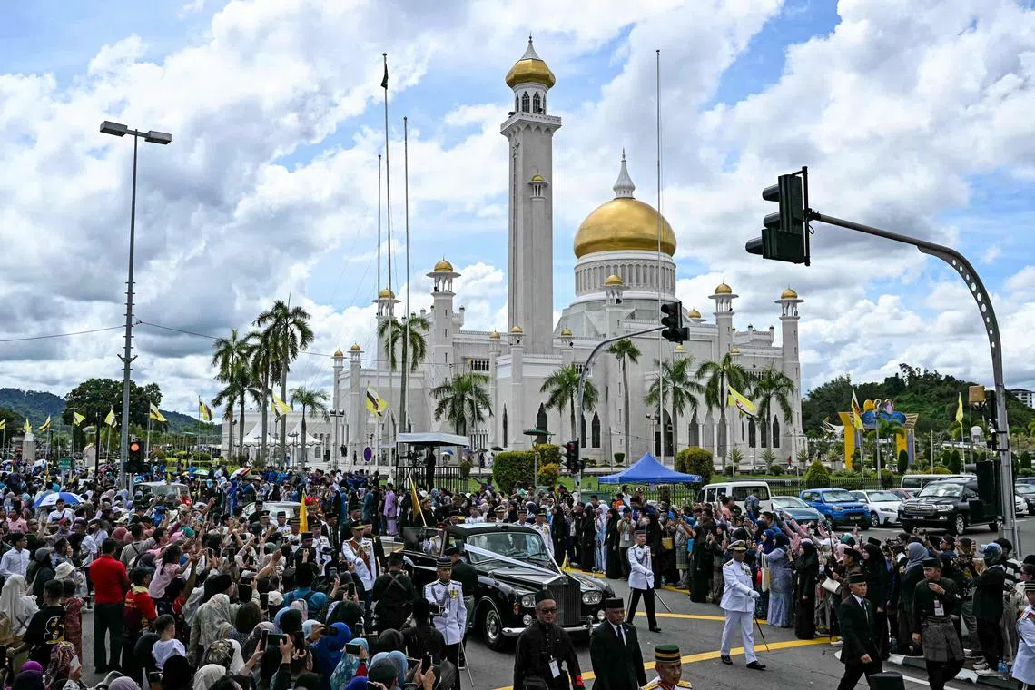 People cheering as the car of Prince Abdul Mateen and his bride Anisha Rosnah drive in front of Sultan Omar Ali Saifuddien Mosque during the wedding procession in Brunei's capital Bandar Seri Begawan on Jan 14, 2024. 