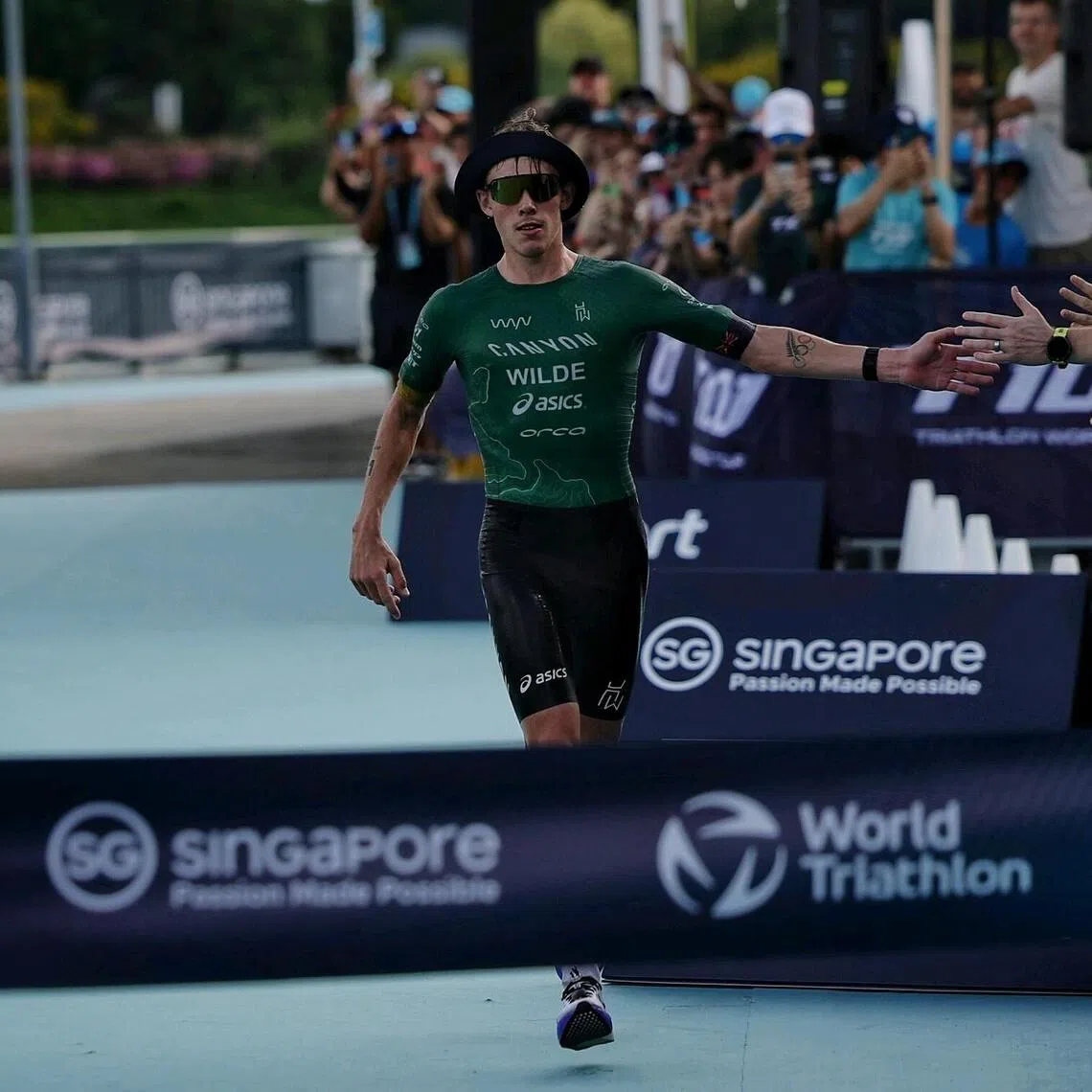 Defending champion Hayden Wilde of New Zealand acknowledging the fans as he approaches the finish line to win the Singapore T100 pro race on April 25, 2026.