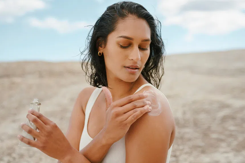 Best Japanese sunscreen: Indian woman applying sunscreen outdoors at the beach