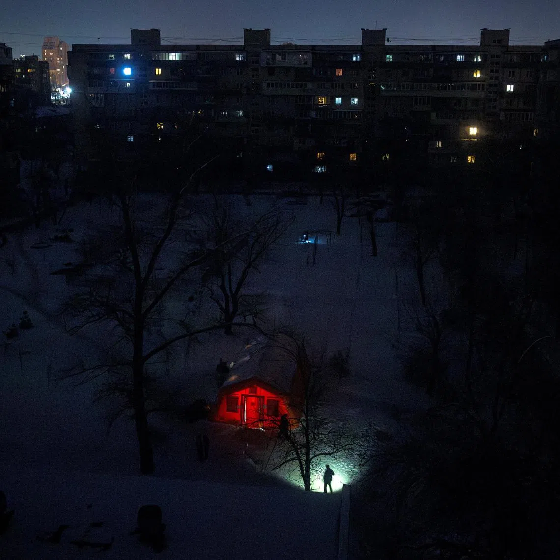 A person carrying a torch approaches a tent provided by emergency services for residents whose apartments are left without heating during sub-zero temperatures, amid Russia's attack on Ukraine, during a winter night in Kyiv, Ukraine, January 17, 2026. REUTERS/Thomas Peter