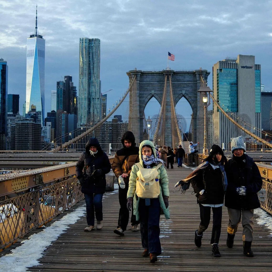 People brace the cold temperatures while walking on the Brooklyn Bridge in New York City.