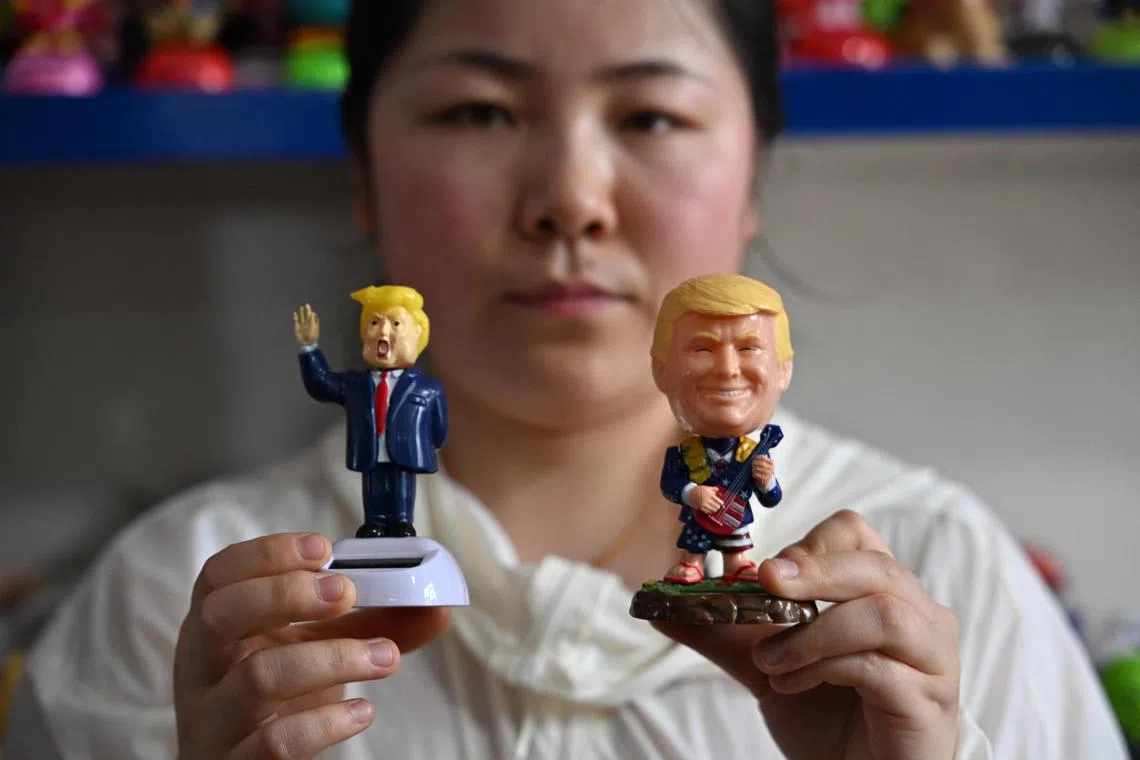 Sales staff Cassie poses with a bobbing statue of US President Donald Trump at a factory in Zhejiang province.
