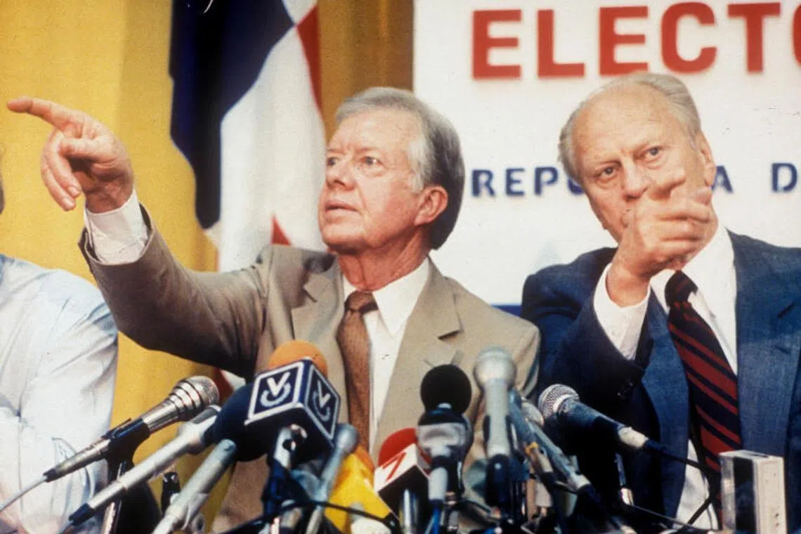 Former U.S. Presidents Jimmy Carter and Gerald Ford point in different directions while calling on reporters wanting to ask questions at a press conference in Panama City, Panama, May 5, 1989. REUTERS/Dematteis/File Photo