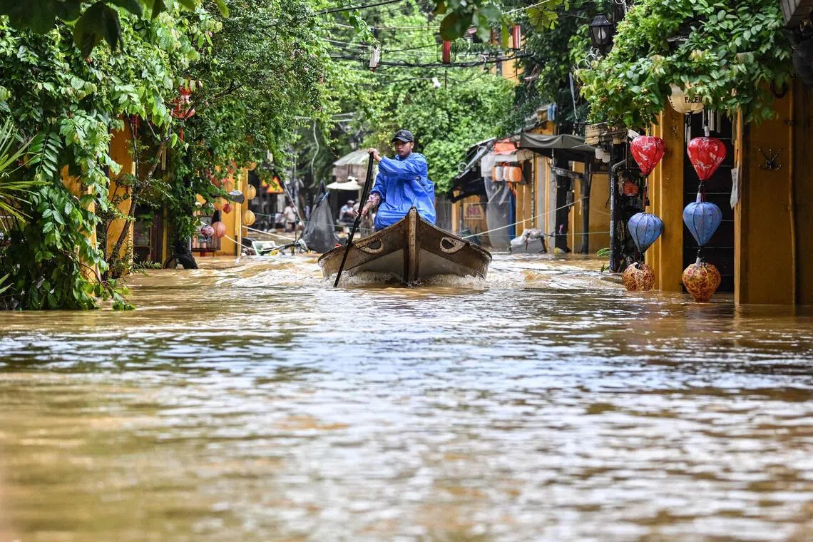 A man navigates a flooded street on a boat following heavy rains in Hoi An on Oct 30, 2025.