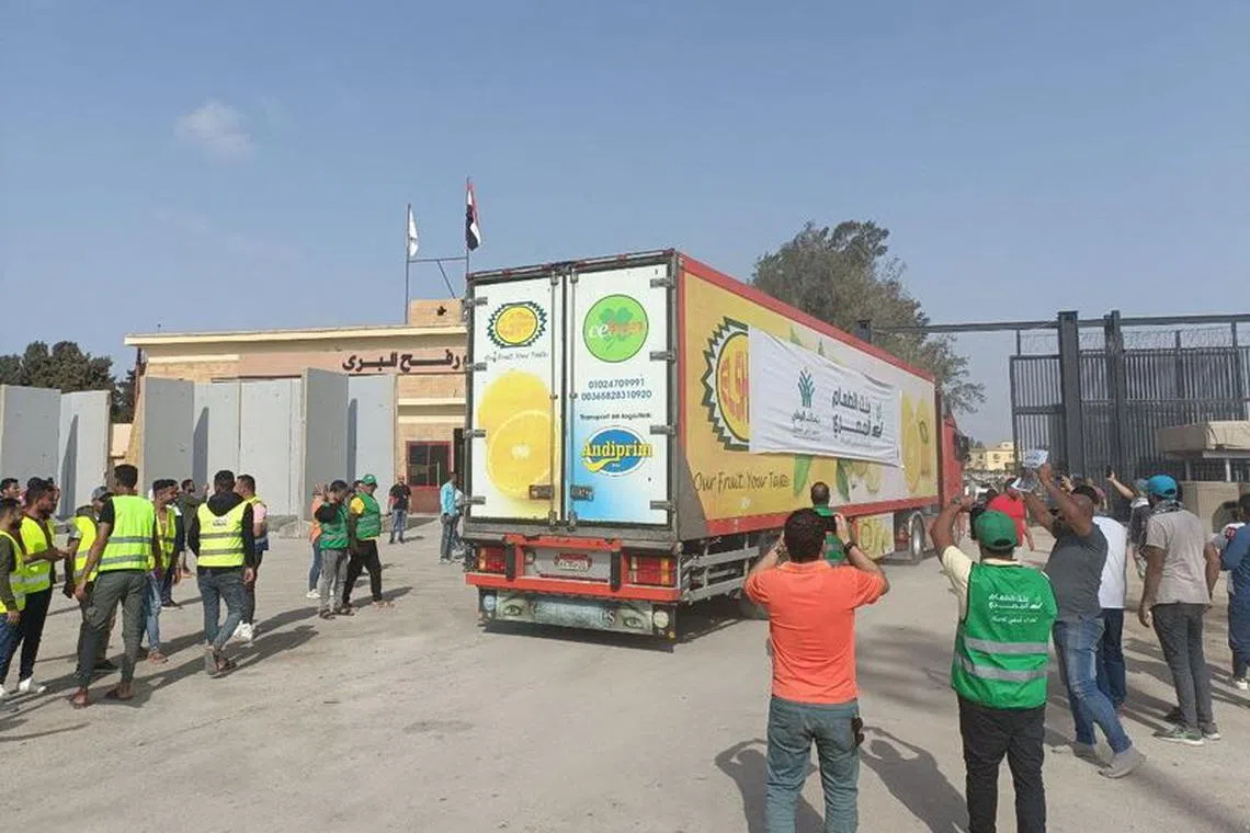 Egyptian volunteers gather next to a truck carrying humanitarian aid as it drives through the Rafah crossing from the Egyptian side, amid the ongoing conflict between Israel and the Palestinian Islamist group Hamas, in Rafah, Egypt October 22, 2023. REUTERS/Stringer