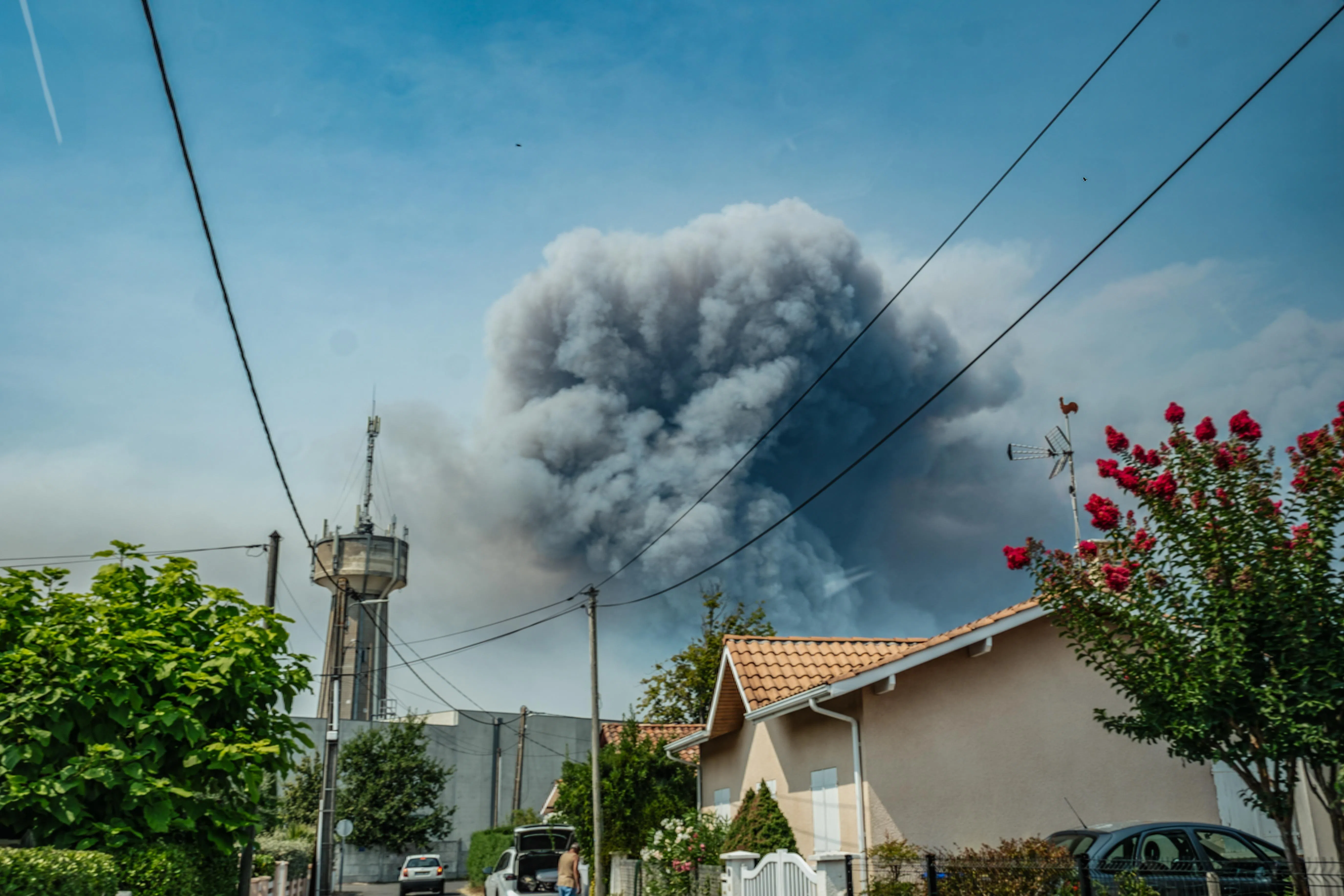 epa13131005 Smoke from a wildfire spreading on Cap Ferret peninsula is seen over houses in Andernos, south-western France, 24 July 2026. French Interior Minister Laurent Nunez confirmed that around 40,000 people are being evacuated from the Cap Ferret peninsula due to the wildfires following a total evacuation order issued by authorities for the southwestern region.  EPA/ASTRID LAGOUGINE