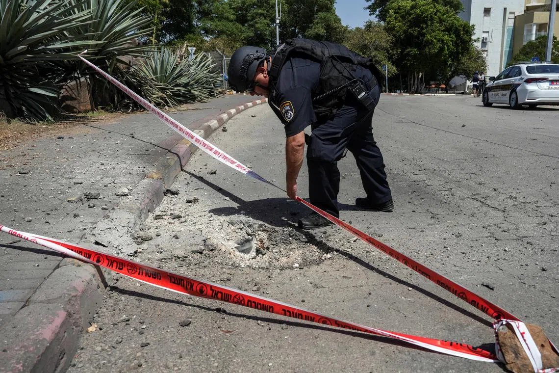 An Israeli police officer checks the impact site of a rocket fired from Lebanon.