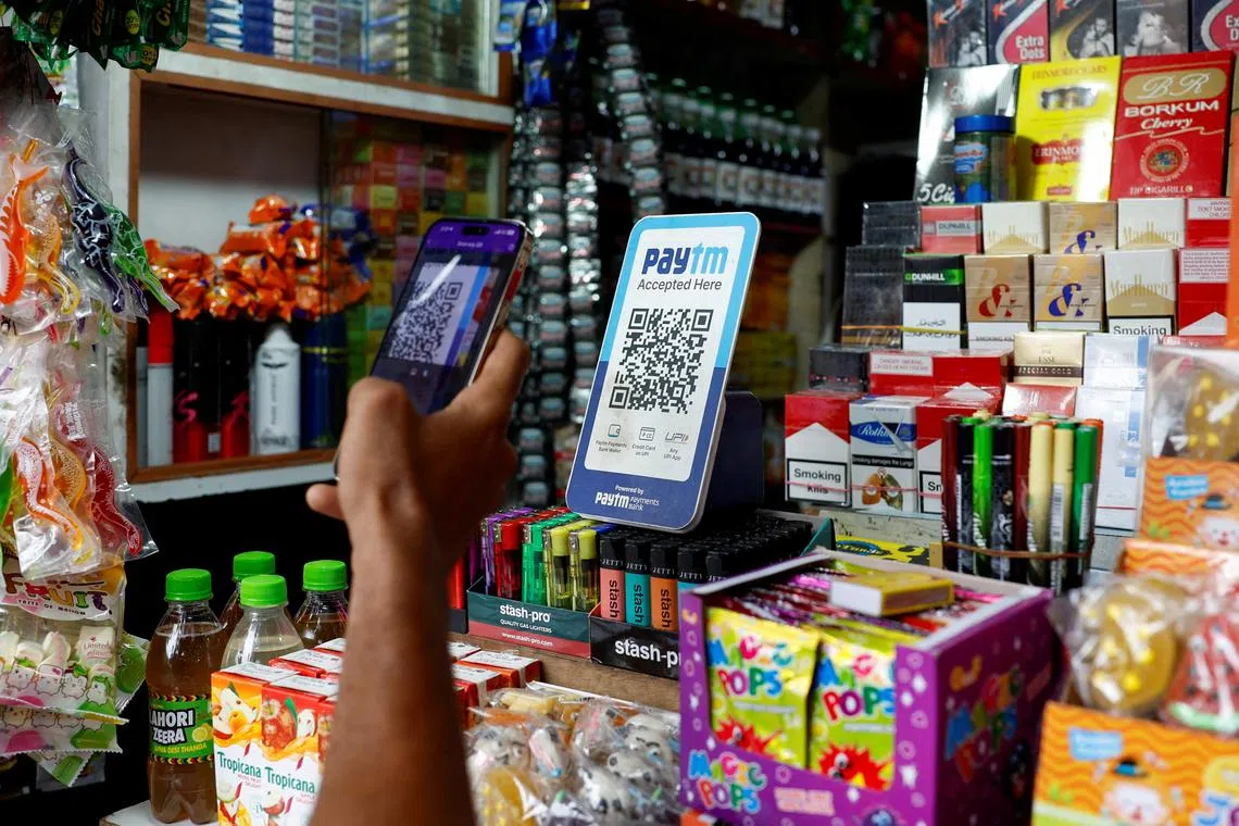 FILE PHOTO: A man uses his phone to scan a QR code of the digital payment app Paytm after purchasing a cold beverage at a shop in Kolkata, India on July 9, 2024. REUTERS/Sahiba Chawdhary/File Photo