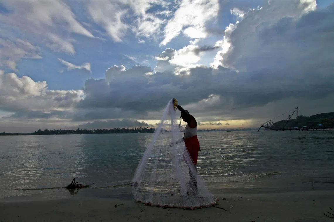 FILE PHOTO: A fisherman arranges his fishing net at a beach against the backdrop of pre-monsoon clouds in the southern Indian city of Kochi June 5, 2014.  REUTERS/Sivaram V./File Photo