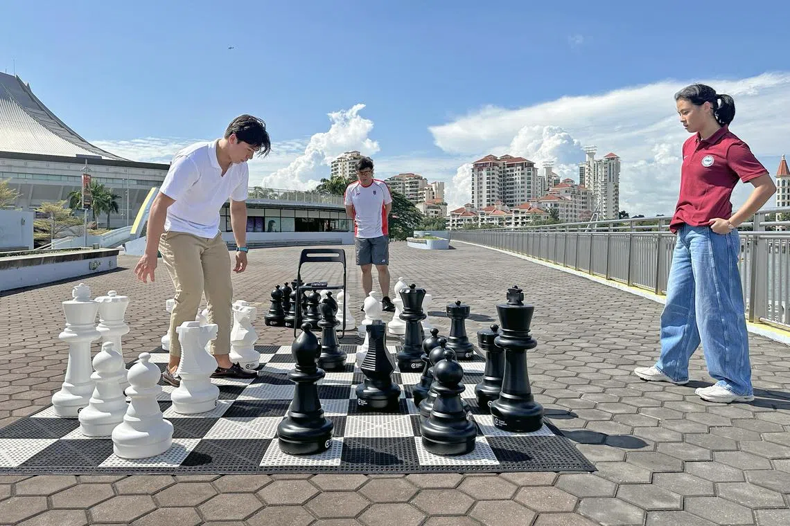 Kitefoiler Max Maeder takes on footballer Danellle Tan in a game of blitz chess as Kevin Goh, CEO of Singapore Chess Federation, plays referee. 