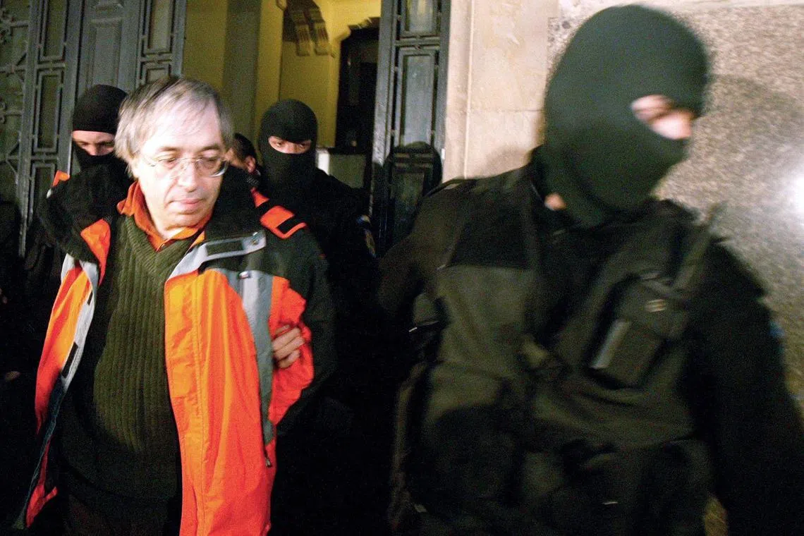 A 2004 photo shows Gregorian Bivolaru (left), the spiritual leader of the MISA sect, being escorted from a courtroom in Bucharest by special police force officers.