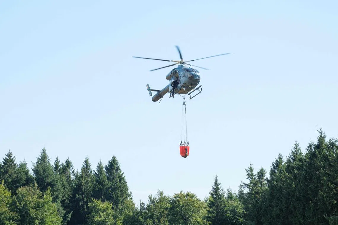 A Belgian police helicopter preparing to drop water over a wildfire in Belgium’s High Fens nature reserve on Aug 14.