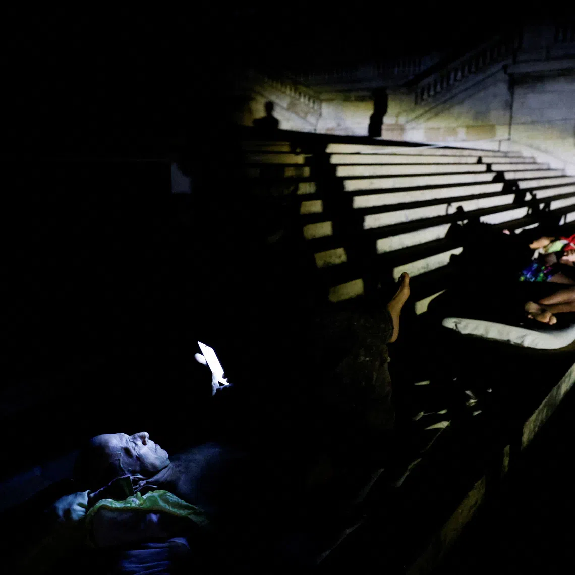 People sleep and rest outdoors on the steps of the University of Havana to escape the heat after Cuba's electricity grid collapsed late on Sunday, plunging the island of about 10 million people into darkness as blackouts become more frequent, in Havana, Cuba August 3, 2026. REUTERS/Norlys Perez