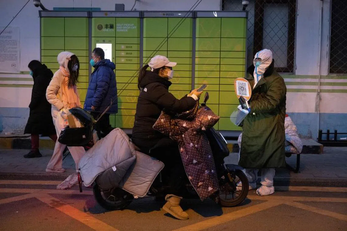 A woman presents her health code to a pandemic prevention worker in a protective suit to enter a residential compound as coronavirus disease (COVID-19) outbreaks continue in Beijing, December 4, 2022. REUTERS/Thomas Peter/File photo