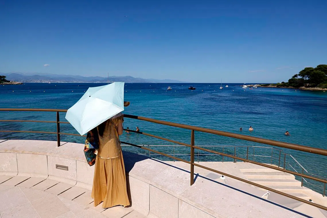 A woman shelters from the sun under an umbrella at Cap d’Antibes, southern France, on Jul 2.