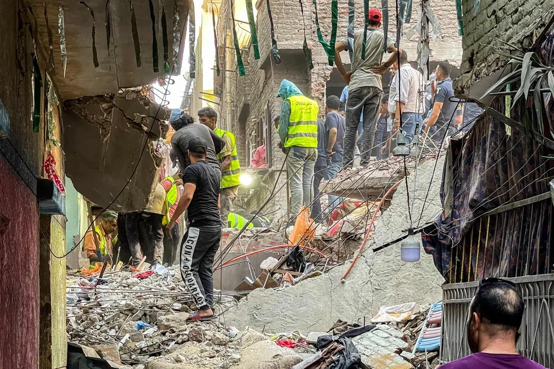 First responders and locals search for survivors in the rubble at the scene of a building collapse in Cairo.