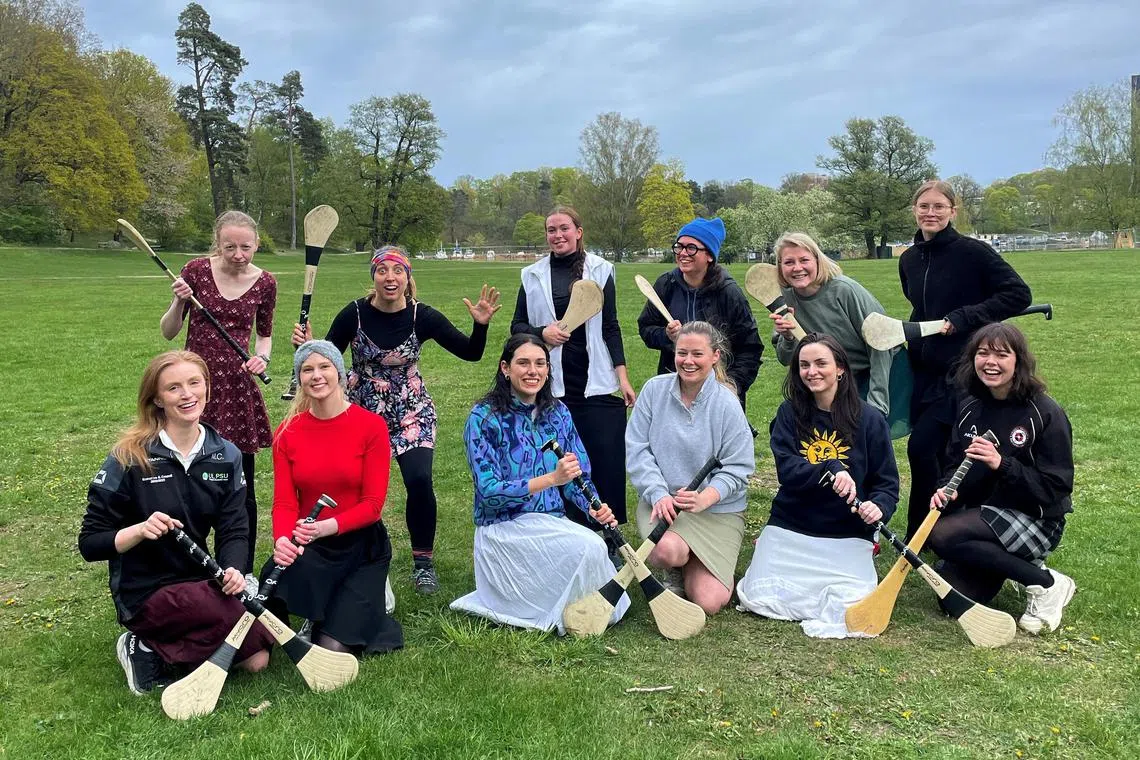 Stockholm Gaels camogie players in skirts  pose with their "caman" or hurling sticks in Sweden on May 10, 2025 in solidarity with the Ireland Camogie players after the ban on women wearing shorts.