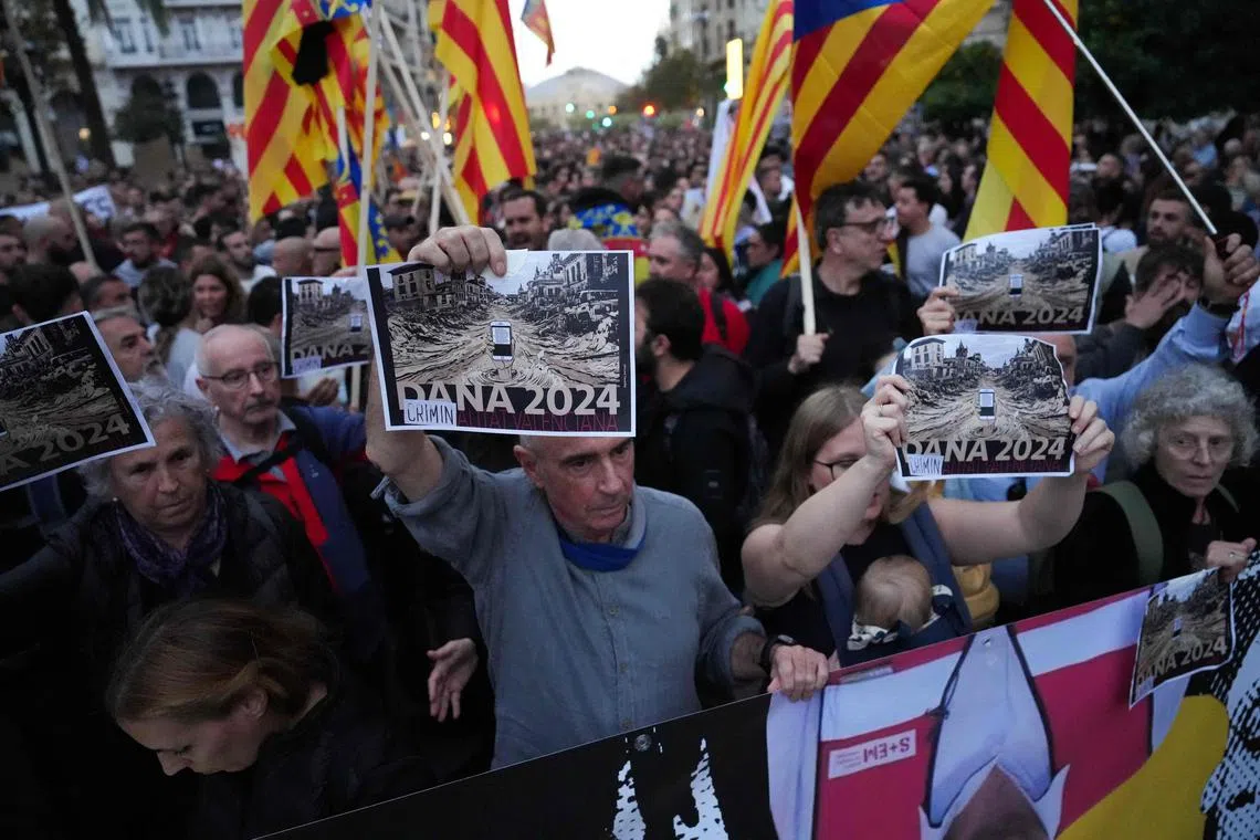 Protesters hold up signs showing depictions of flood damage as they demand the resignation of Valencia regional president Carlos Mazon, in Valencia, on Nov 9.
